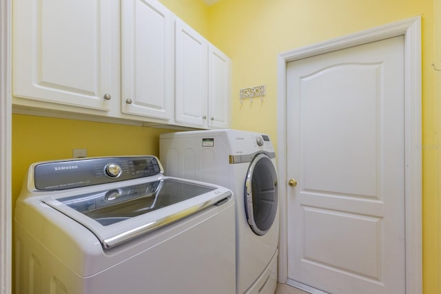 clothes washing area featuring washing machine and clothes dryer and cabinet space