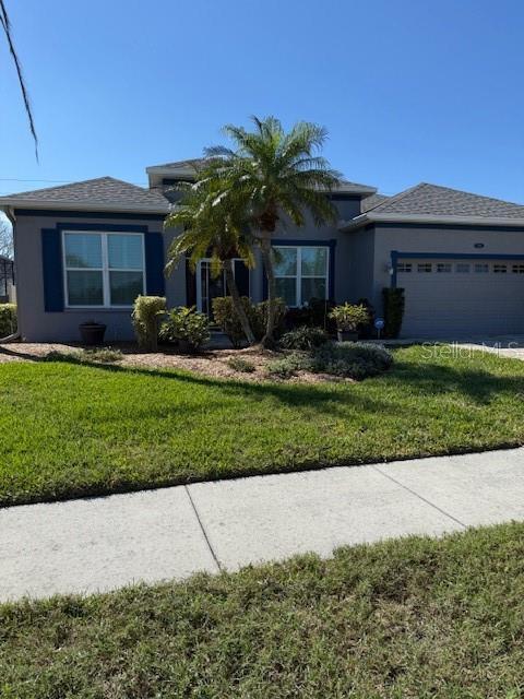 view of front of house with stucco siding, an attached garage, and a front yard