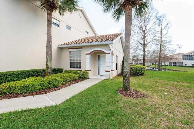 view of front of house featuring a front lawn, a tile roof, and stucco siding