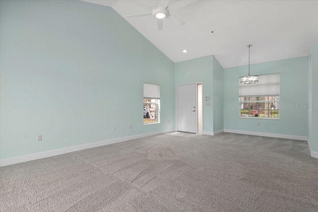 unfurnished room featuring high vaulted ceiling, baseboards, carpet flooring, and ceiling fan with notable chandelier