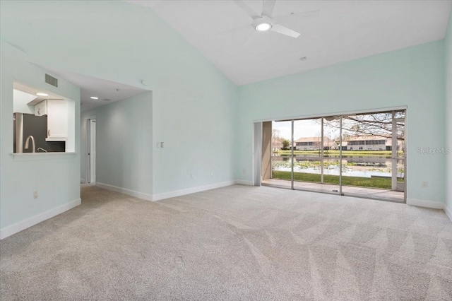 spare room featuring high vaulted ceiling, light colored carpet, visible vents, and baseboards