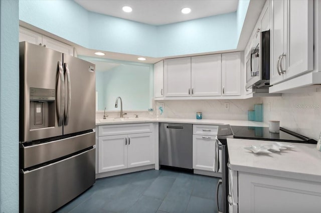 kitchen with stainless steel appliances, light countertops, backsplash, white cabinetry, and a sink