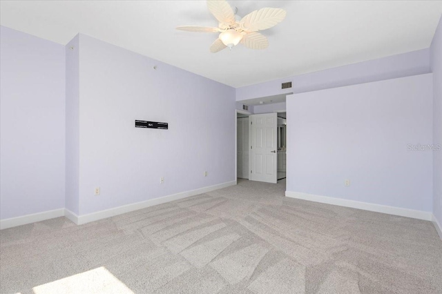 spare room with baseboards, visible vents, a ceiling fan, and light colored carpet