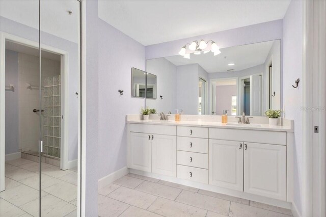 full bath with a sink, a tile shower, baseboards, and double vanity