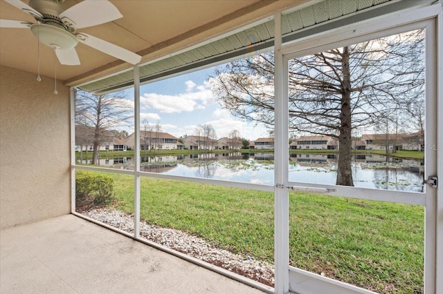 unfurnished sunroom featuring a water view, a residential view, and a ceiling fan