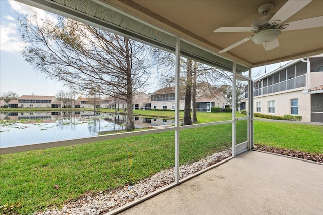 unfurnished sunroom with a water view, ceiling fan, and a residential view