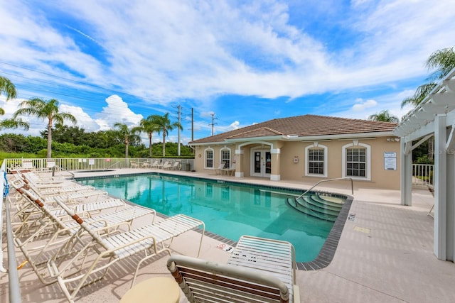 pool with french doors, a patio area, and fence