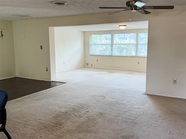 spare room with carpet floors, visible vents, ceiling fan, and baseboards