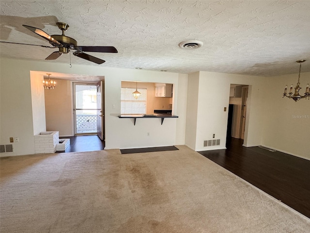 unfurnished living room with visible vents, dark carpet, and a textured ceiling