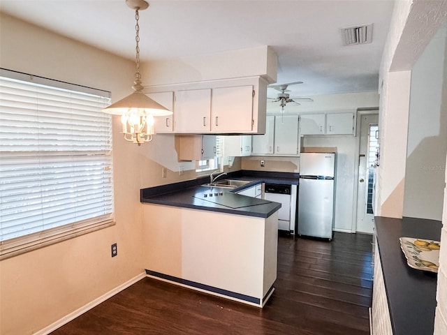 kitchen featuring a sink, visible vents, freestanding refrigerator, dishwasher, and dark countertops