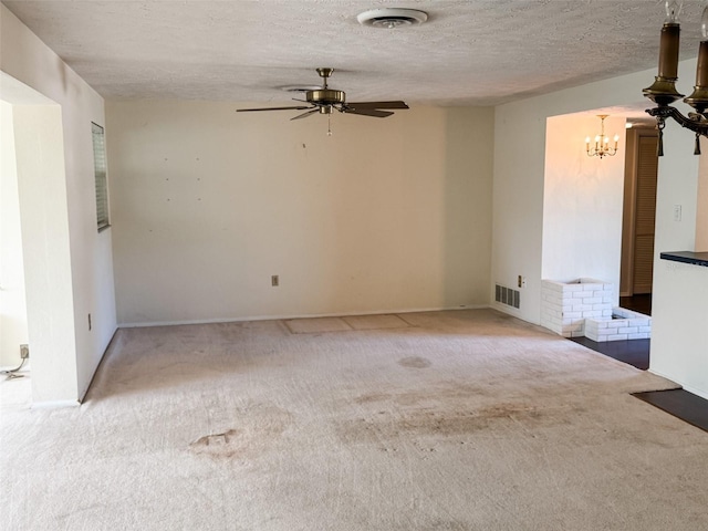 carpeted spare room featuring visible vents, a textured ceiling, and ceiling fan with notable chandelier