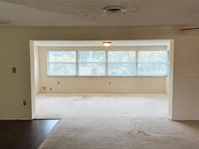 carpeted spare room featuring visible vents and a textured ceiling