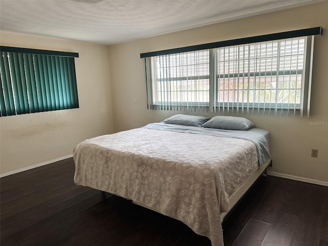 bedroom featuring wood-type flooring, multiple windows, and baseboards