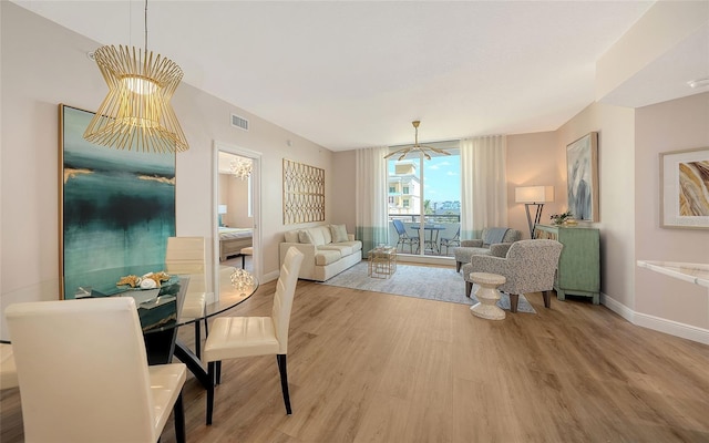 living area with baseboards, visible vents, a chandelier, and wood finished floors