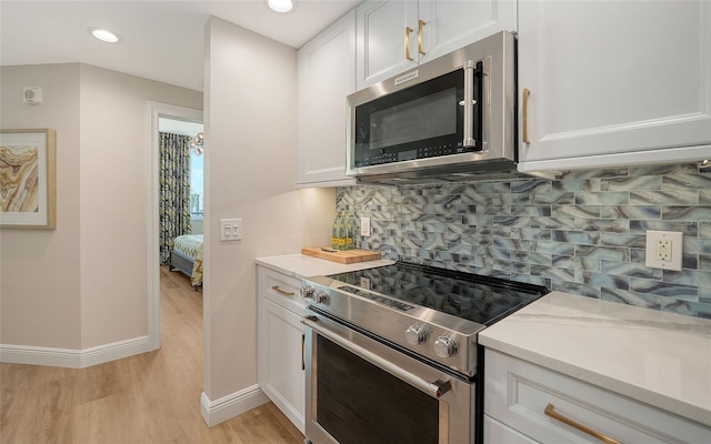 kitchen featuring light wood finished floors, tasteful backsplash, light countertops, appliances with stainless steel finishes, and white cabinets