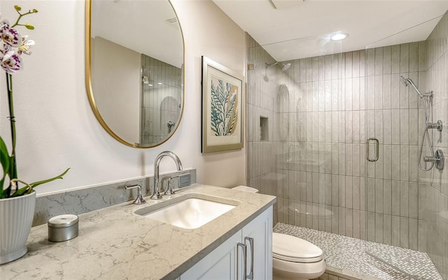 full bathroom with a stall shower, vanity, and toilet