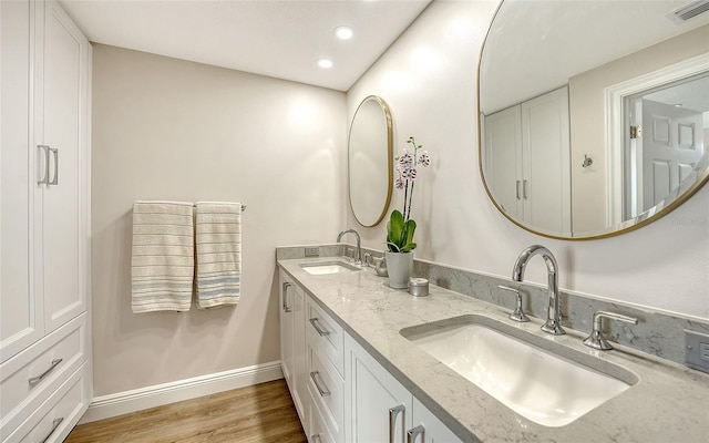 bathroom featuring visible vents, a sink, baseboards, and wood finished floors