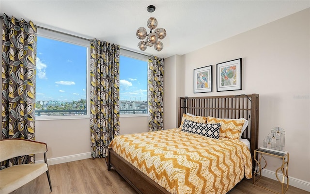 bedroom featuring a chandelier, wood finished floors, and baseboards