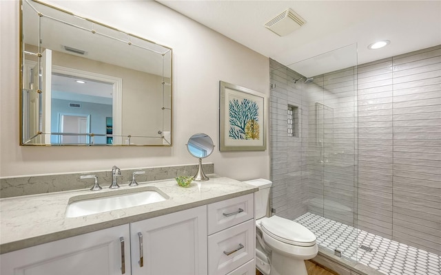 bathroom with toilet, vanity, a shower stall, and visible vents