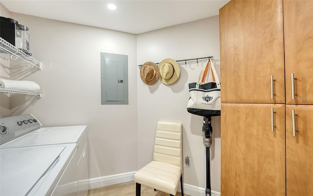 washroom featuring wood finished floors, baseboards, washer and dryer, cabinet space, and electric panel