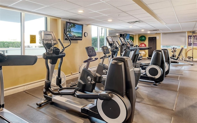 gym with a drop ceiling and baseboards