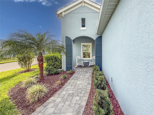 entrance to property with covered porch and stucco siding