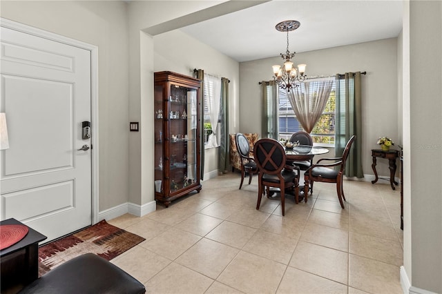 dining space featuring light tile patterned floors, baseboards, and an inviting chandelier