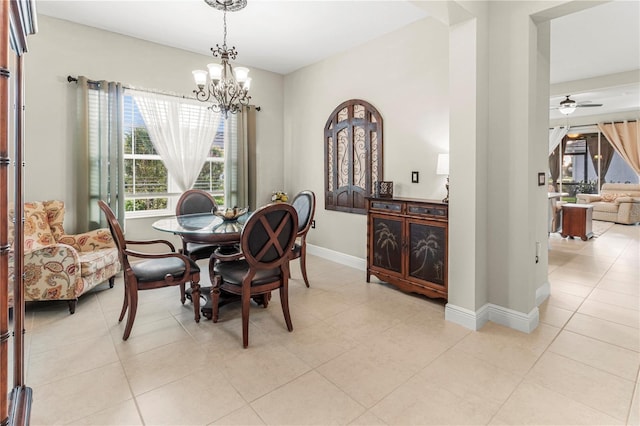 dining area featuring ceiling fan with notable chandelier, baseboards, and light tile patterned floors