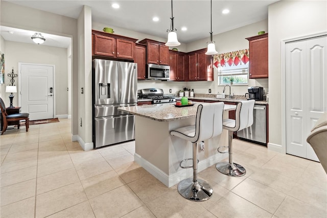 kitchen featuring light tile patterned flooring, stainless steel appliances, light stone counters, and a center island