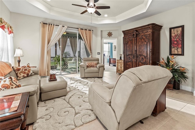 living area with a ceiling fan, a raised ceiling, ornamental molding, and light tile patterned floors