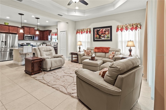 living area with a raised ceiling, light tile patterned flooring, crown molding, and visible vents