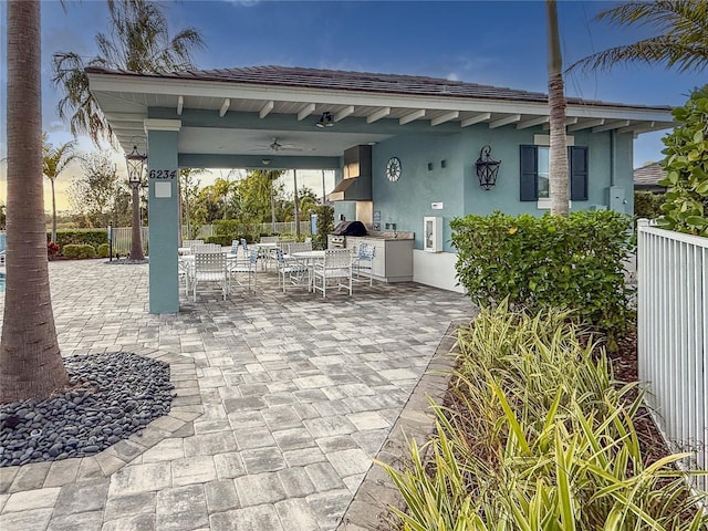 view of patio / terrace featuring outdoor dining area, a ceiling fan, a grill, fence, and exterior kitchen