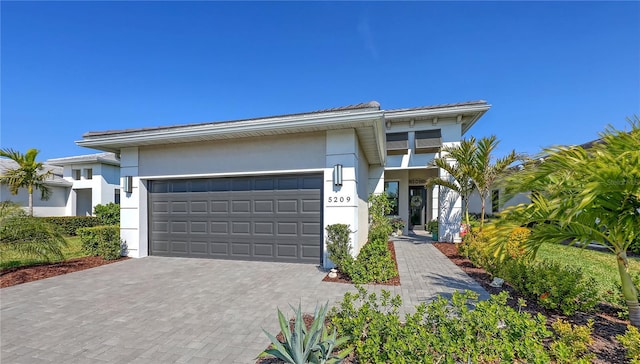 view of front facade with a garage, decorative driveway, and stucco siding