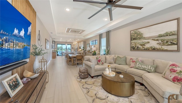 living area with a ceiling fan, a tray ceiling, wood finished floors, and recessed lighting