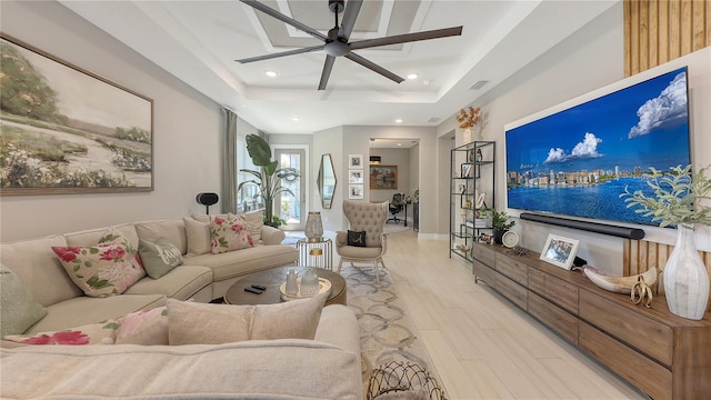 living room with a ceiling fan, a tray ceiling, light wood-style flooring, and recessed lighting