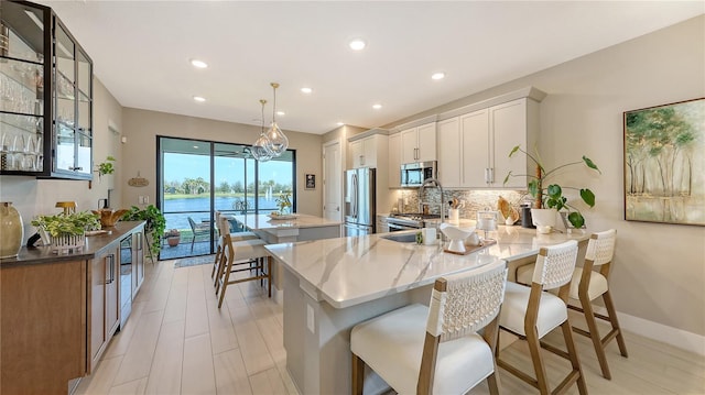 kitchen featuring a kitchen island, a peninsula, stainless steel appliances, white cabinetry, and backsplash