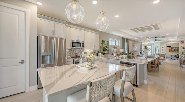 kitchen featuring a tray ceiling, stainless steel appliances, open floor plan, a kitchen island, and a peninsula