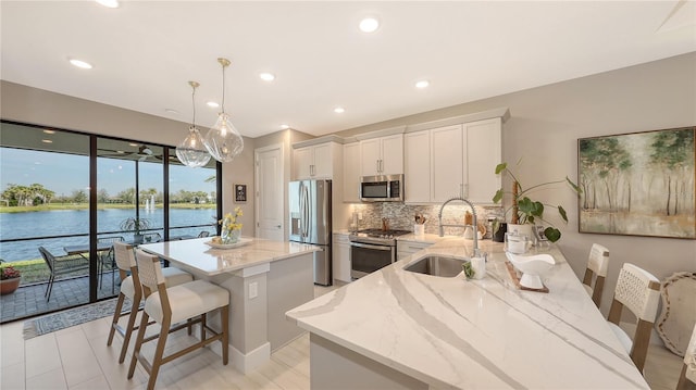 kitchen featuring appliances with stainless steel finishes, a center island, a sink, light stone countertops, and backsplash