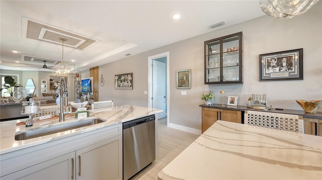 kitchen with visible vents, a raised ceiling, light stone counters, pendant lighting, and stainless steel dishwasher