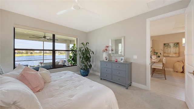 bedroom with a ceiling fan, a water view, light colored carpet, and baseboards