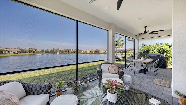 sunroom featuring a wealth of natural light, a water view, and a ceiling fan