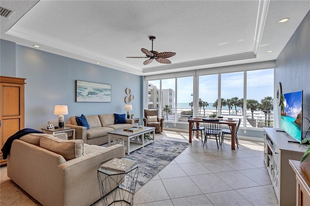 living room featuring a textured ceiling, light tile patterned flooring, visible vents, a ceiling fan, and a raised ceiling