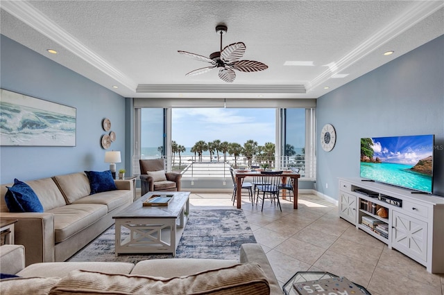 living room with a textured ceiling, ceiling fan, light tile patterned floors, and a raised ceiling