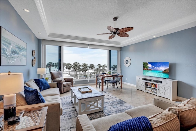 living room with light tile patterned floors, a tray ceiling, a textured ceiling, and baseboards