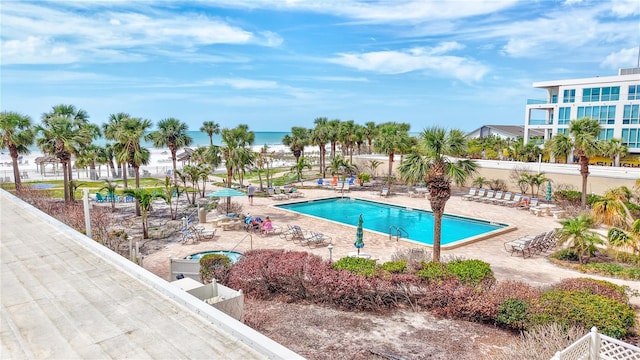 pool with a patio, a water view, and fence