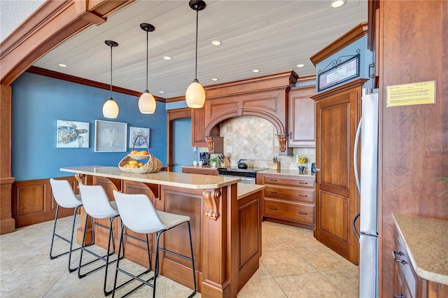 kitchen featuring decorative backsplash, a kitchen island, brown cabinets, a kitchen breakfast bar, and crown molding