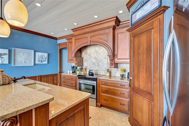 kitchen featuring appliances with stainless steel finishes, brown cabinetry, a sink, and crown molding