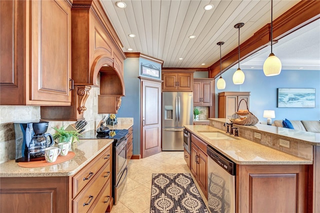 kitchen with decorative backsplash, appliances with stainless steel finishes, brown cabinetry, a sink, and light stone countertops