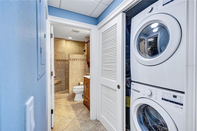 laundry area with laundry area, light tile patterned floors, and stacked washer / drying machine