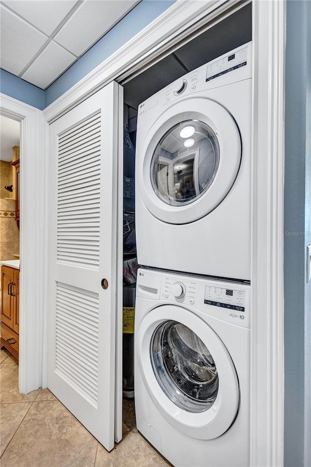 laundry area featuring stacked washer / dryer, laundry area, and light tile patterned flooring